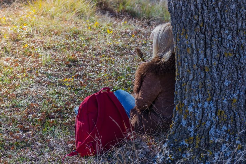 Hiker woman rests near tree