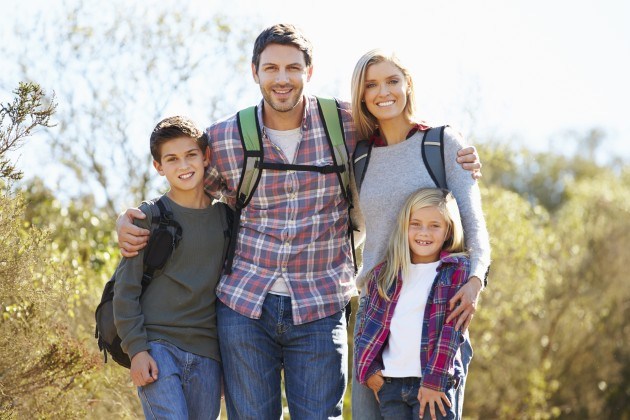Family hiking in countryside wearing backpacks