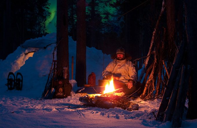 Man sitting on log near campfire in the camping