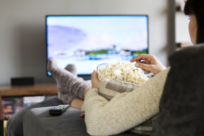 woman watching TV and eating popcorn