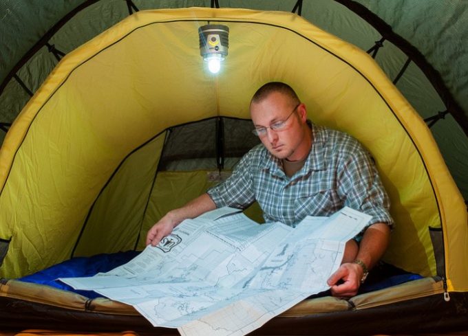 man looking on map in tent