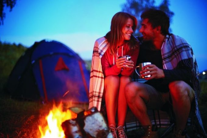 couple smiling near campfire
