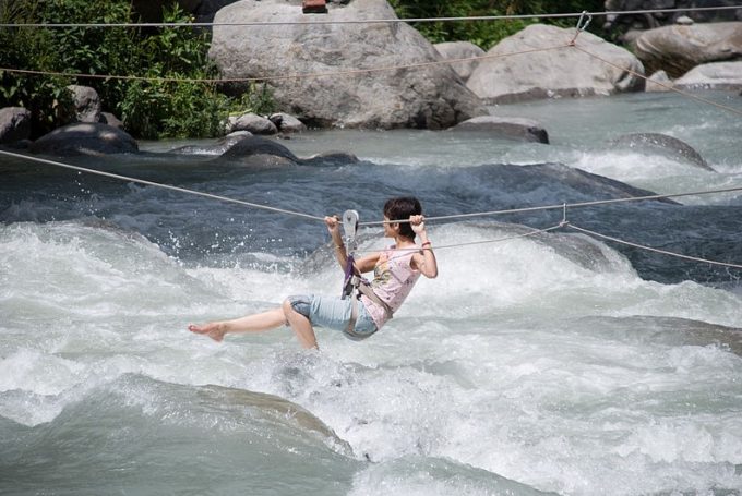 woman crossing river with zip line